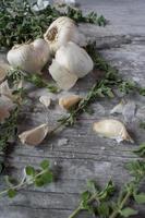garlic bulbs and oregano stalks on rustic wood top view photo