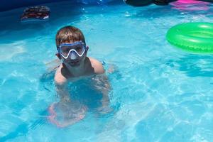 smiling young boy in swim goggles at pool photo