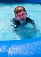 smiling young boy in swim goggles at pool photo