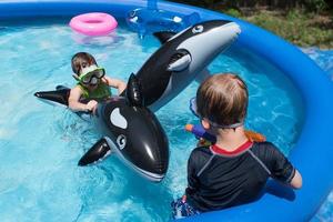 two boys riding swim floats in pool with goggles photo