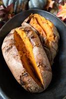 baked sweet potatoes sliced open with butter in fall setting