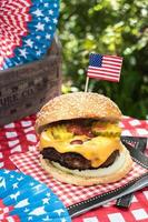 Fourth of July cheese burger with American flag on picnic table outdoors photo