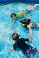 niños pequeños tomados de la mano bajo el agua con gafas en la piscina foto