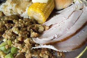 closeup of Thanksgiving meal of turkey, stuffing, corn, and bread photo