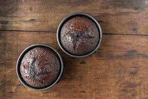 two baked round mini chocolate cakes on wooden background flat lay photo