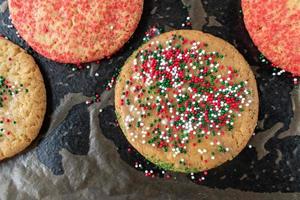 baking sheet of baked sugar cookies with red and green sprinkles flat lay photo