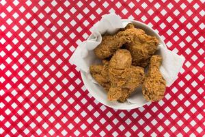 Fried chicken in white bowl on red and white checkered table flat lay photo