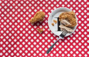 Fried chicken basket on red checkerboard tablecloth flat lay photo