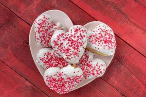 Valentines Day doughnuts on heart shaped plate on rustic red background photo