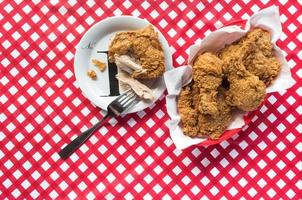 Fried chicken basket on red checkerboard tablecloth flat lay photo