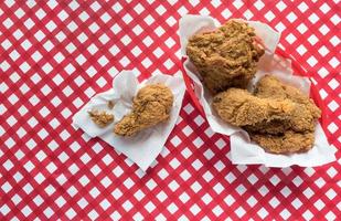 Fried chicken basket on red checkerboard tablecloth flat lay photo