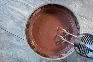 mixing chocolate pudding with hand mixer in large bowl flat lay photo