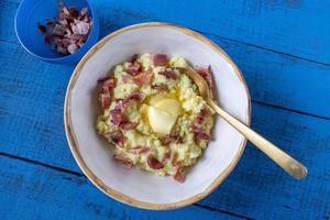 bowl of breakfast grits with butter and bacon bits top view photo