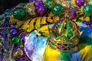 Mardi Gras King Cake topped with crown surrounded by beads and decorations photo