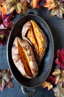 baked sweet potatoes sliced open with butter in fall setting