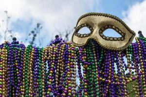 iron fence covered with Mardi Gras beads topped with mask photo