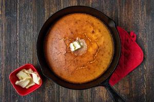 baked homemade cornbread with butter in cast iron pan flat lay photo