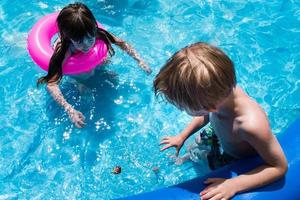 niños mirando el juguete de natación en la piscina de verano brillante foto