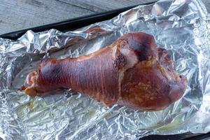 Giant baked turkey leg on tin foil baking pan top view photo