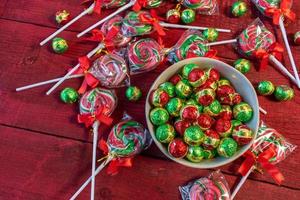 caramelos de navidad chocolates y piruletas sobre fondo rojo plano foto