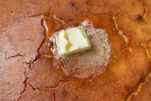 Primer plano de pan de maíz casero con mantequilla derretida foto