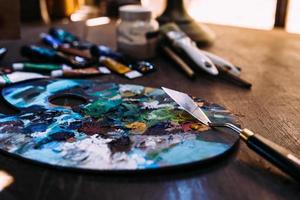 Palette in paint and a palette knife on a wooden table. photo