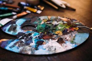 Palette in paint and a palette knife on a wooden table. photo