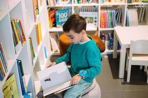 un niño alcanza un estante de libros para niños en la librería. foto