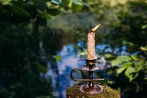 Burning candle in enchanted forest. Occult, esoteric concept.