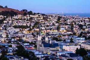 vista de la colina del vecindario de la hora dorada de las casas de san francisco, techos puntiagudos, coloridos y pintorescos con algunas casas victorianas, una vista típica de san francisco. foto