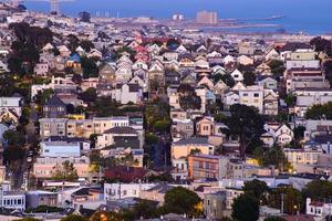 vista de la colina del vecindario de la hora dorada de las casas de san francisco, techos puntiagudos, coloridos y pintorescos con algunas casas victorianas, una vista típica de san francisco. foto