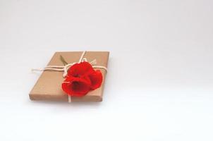 regalo envuelto en papel artesanal en la parte superior se encuentra un ramo de amapolas rojas foto