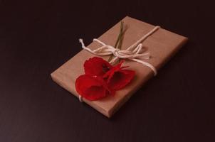 gift is wrapped in craft paper on top lies a bouquet of red poppies photo