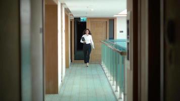 Businesswoman walking down the aisle. Businesswoman holding laptop while walking down corridor. video