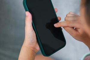 mano que sostiene el concepto de tecnología en línea del teléfono, niño que sostiene el teléfono inteligente cerca de la pantalla negra en blanco foto