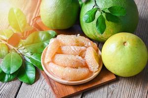 pomelo fruit on wooden plate  background, fresh green pomelo peeled and leaf frome pomelo tree , pummelo , grapefruit in summer tropical fruit  in thailand photo