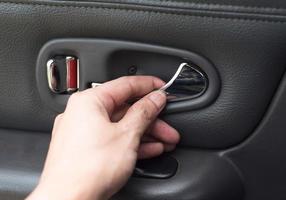 Hand on the inside car handleMan hands to open door pressing button locking doors in car photo