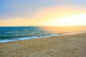 puesta de sol en el mar de la playa con fondo de cielo amarillo nuboso en verano foto