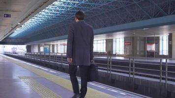 hombre de negocios esperando el metro. hombre de negocios caminando en el metro. se detiene en algún lugar, mira su reloj y espera a que llegue el metro. hombre de negocios moderno con maletín en la mano. video