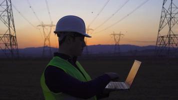 torres elétricas e engenheiro de trabalho. engenheiro trabalhando na frente de torres elétricas, silhueta de engenheiro ao pôr do sol. engenheiro elétrico. video