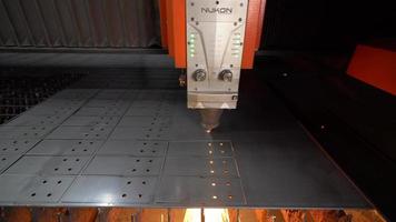 Industrial CNC laser cutting machine. A metal sheet is being cut on a CNC Laser cutting machine. Holes open and sparks come out. Industry. video