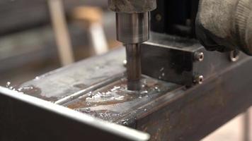 percer des trous dans le profil de fer avec une machine industrielle. le technicien perce un trou dans la machine dans un profilé en fer.