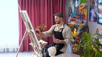 il pittore dipinge a olio con un mezzo colorato. ambiente di lavoro di un pittore di pittura a olio. video