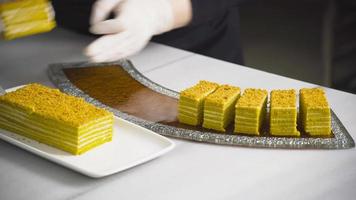 Chef and cake dessert. Chef in white gloves arranges slices of cake on serving plate. video