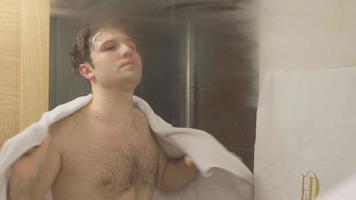 secar com uma toalha após o banho. depois de terminar o banho, o homem está se secando com uma toalha em frente ao espelho do banheiro. video