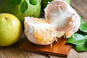 Fresh green pomelo peeled and leaf frome pomelo tree , pomelo fruit on wooden plate  background, pummelo , grapefruit in summer tropical fruit  in thailand photo