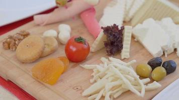 plato de desayuno saludable. aceitunas, queso, queso cheddar, tomates, higos, salami, nueces, albaricoques secos en el plato del desayuno. video