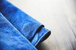 pantalones vaqueros plegados tejido patrón utilizado de blue jeans sobre fondo de madera foto