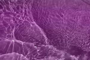 Defocus blurred purple watercolor in swimming pool rippled water detail background. Water splash, water spray background. photo