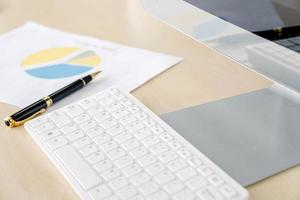 Office desk with monitors keyboards and the different graphs on paper. photo